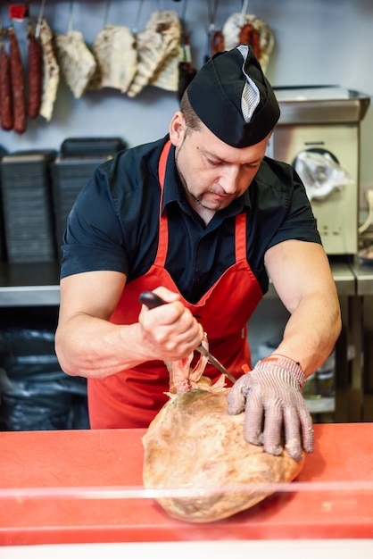 Premium Photo | Butcher boning a ham in a modern butcher shop