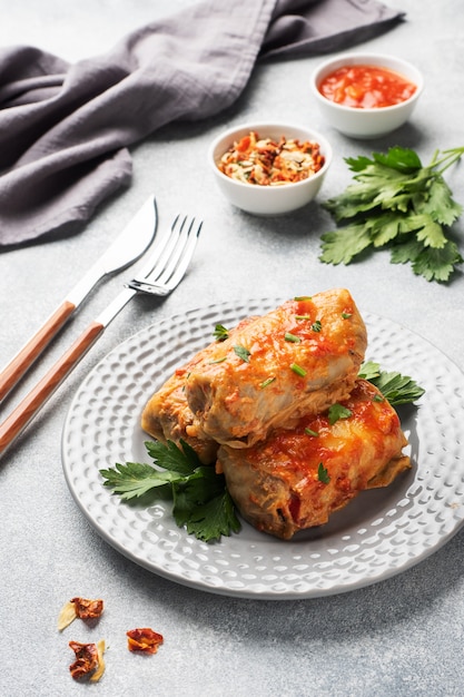 Cabbage rolls with beef, rice and vegetables on the plate. stuffed cabbage leaves with meat. gray concrete table Premium Photo