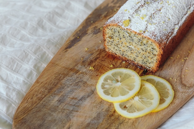 Cake with poppy seeds and lemon zest, sprinkled with powdered sugar. cupcake with lemon on a wooden board. Premium Photo