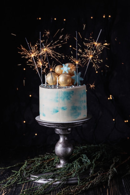 花火とケーキ 装飾されたクリスマスクリームケーキ 暗い背景に線香花火を燃焼 プレミアム写真