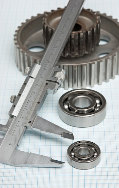 Premium Photo | Caliper with gears and bearings on graph paper