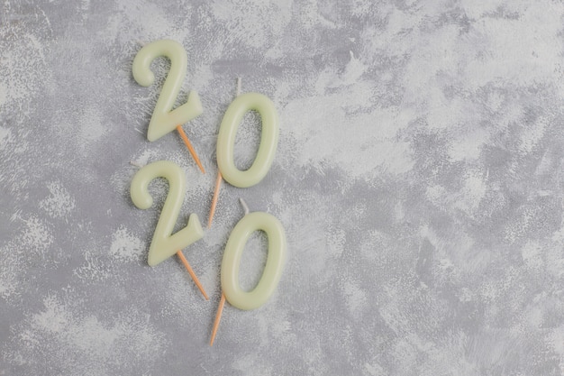 Candles in the shape of numbers 2020 as a symbol of the new year next to christmas shaped sparkle candies on a gray table. top view, flat lay Free Photo