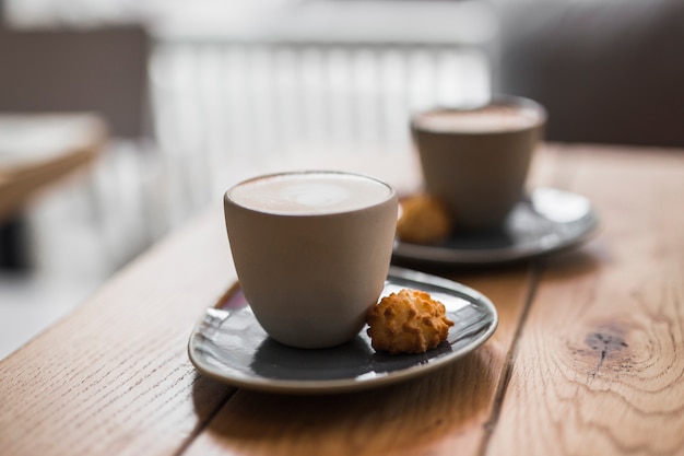 Cappuccino or latte with frothy foam with cookie on wooden table Free Photo