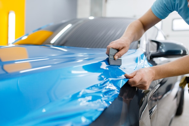 Premium Photo | Car wrapping, mechanic with squeegee installs ...