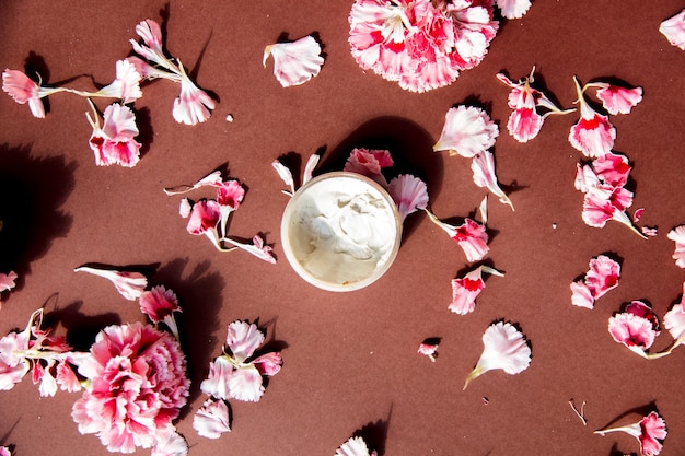 茶色の表面にカーネーションの花びらとスキンケアクリーム プレミアム写真