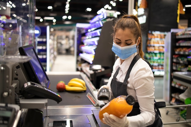 Кассир в супермаркете в маске и перчатках, полностью защищенных от вируса короны Бесплатные Фотографии