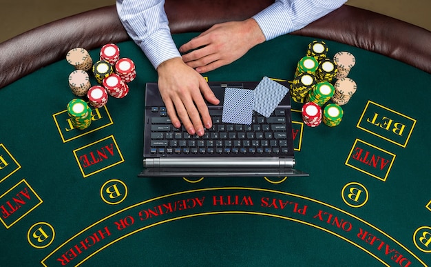 Premium Photo | Casino, online gambling, technology and people concept -  close up of poker player with playing cards, laptop and chips at green  casino table