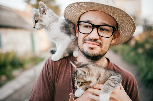 猫好き 自然に2匹の子猫を保持している麦わら帽子の幸せな少年 プレミアム写真