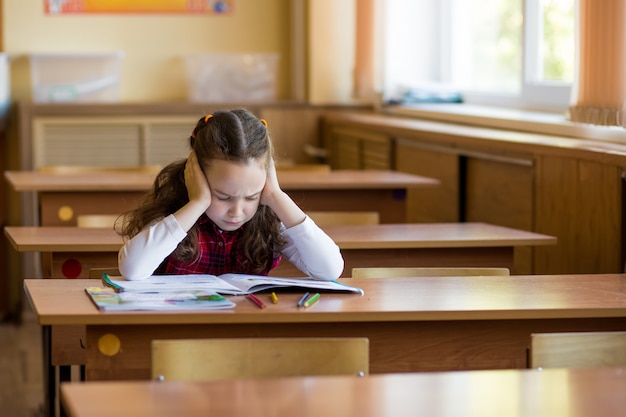 Caucasian girl sitting at desk in class room and hard to learn lessons. preparation for exams, tests Premium Photo