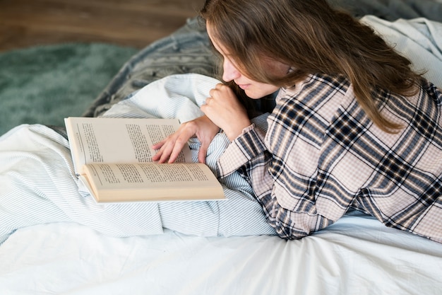 Caucasian woman reading book in bed Free Photo