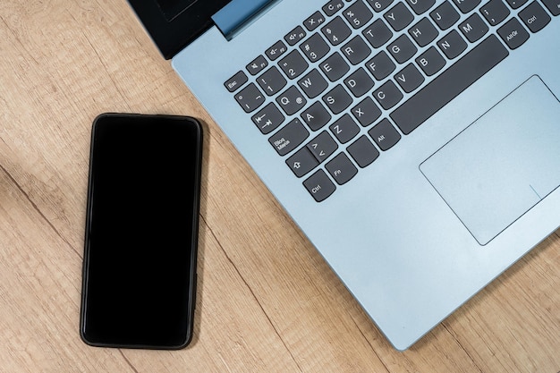 Premium Photo | Cell phone next to an open laptop on a table ...