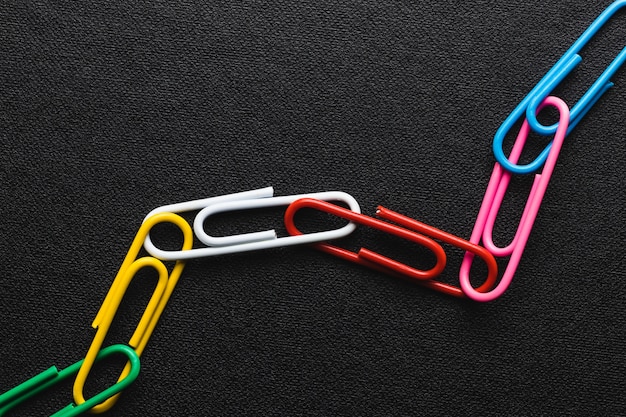 Chain made of paper clips on black background,teamwork and ...