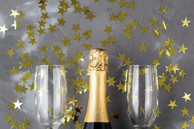 シャンパンのボトルとゴールドの紙吹雪の星が付いたグラス クリスマス 新年 誕生日または結婚式のコンセプト プレミアム写真