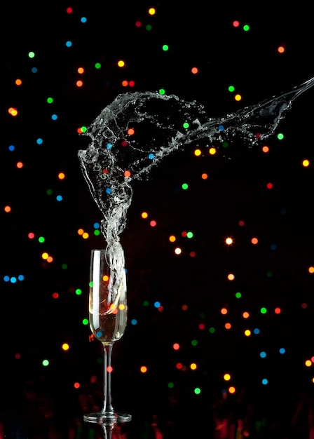 Champagne flute with splash and colored lights | Premium Photo