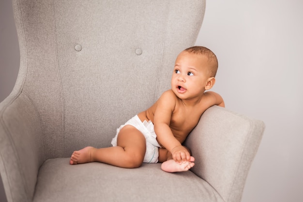 椅子に座っているおむつの魅力的なアフリカ系アメリカ人の赤ちゃん プレミアム写真