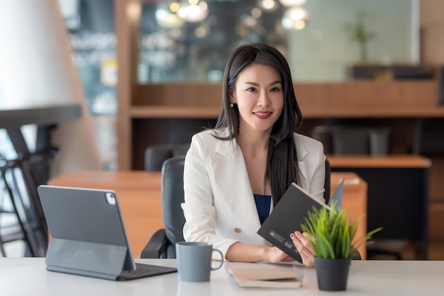 Premium Photo | Charming asian businesswoman holding a notebook looking