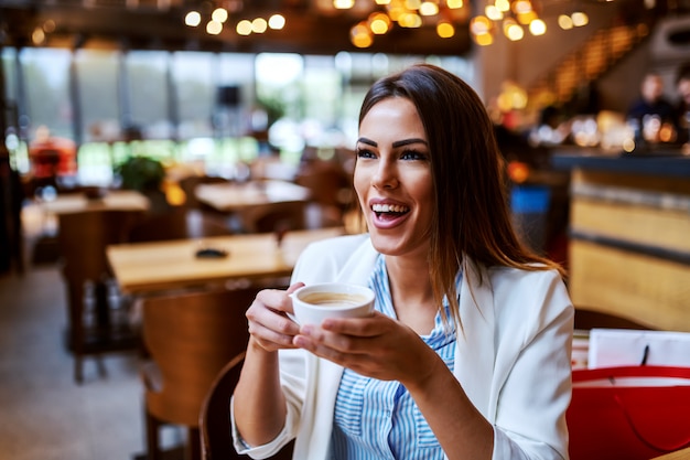 Premium Photo | Charming caucasian laughing brunette sitting in cafeteria