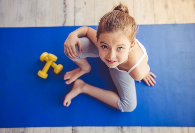 Premium Photo | Charming little girl is sitting on yoga mat