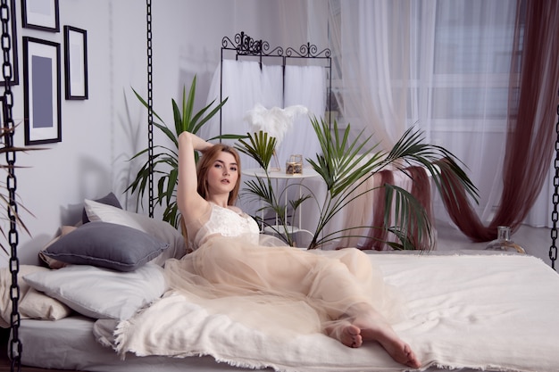 美しいネグリジェで魅力的なセクシーな女の子が寝室の大きなベッドに横たわっています プレミアム写真