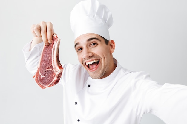 Premium Photo | Cheerful chef cook wearing uniform showing raw beef ...