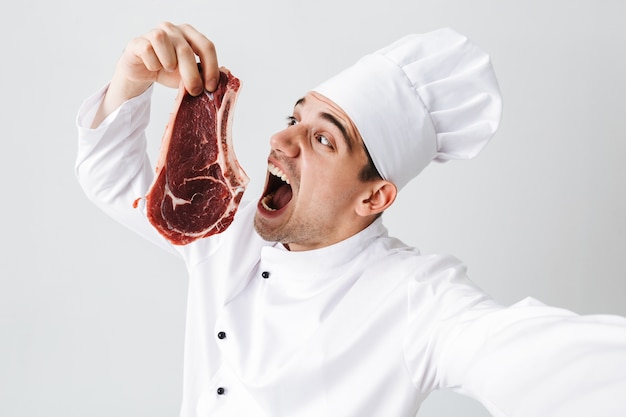 Premium Photo | Cheerful chef cook wearing uniform showing raw beef ...