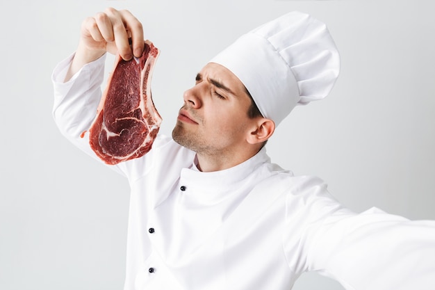 Premium Photo | Cheerful chef cook wearing uniform showing raw beef ...