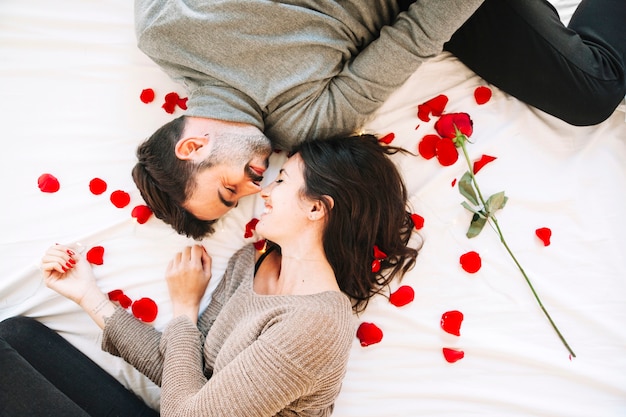 Cheerful couple touching noses on rose petals | Free Photo
