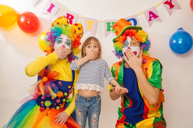 Premium Photo | Cheerful emotional clowns on a holiday with a girl show ...