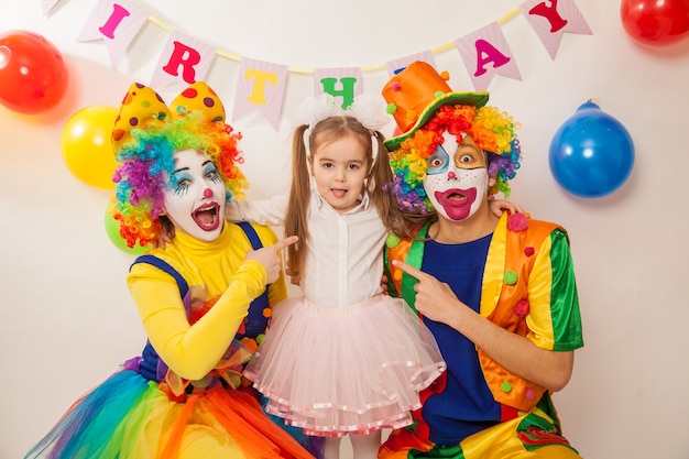 Premium Photo | Cheerful emotional clowns on a holiday with a girl ...