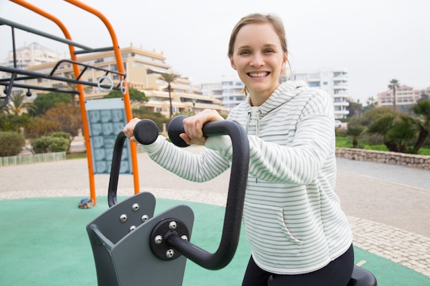 Cheerful fit girl working out on exercise bike Free Photo