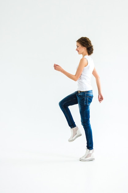 Premium Photo Cheerful Girl In A White T Shirt And Dark Blue Jeans Stands Sits Runs