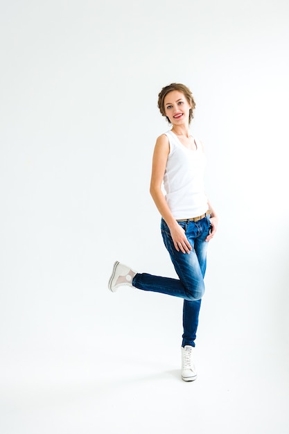 Premium Photo Cheerful Girl In A White T Shirt And Dark Blue Jeans Stands Sits Runs