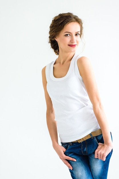 Premium Photo Cheerful Girl In A White T Shirt And Dark Blue Jeans In The Studio On A White Background Stands Sits Runs