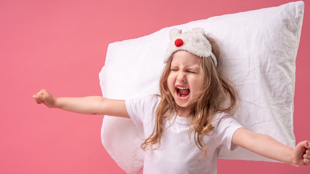 Premium Photo | Cheerful little girl in a sleep mask with a pillow