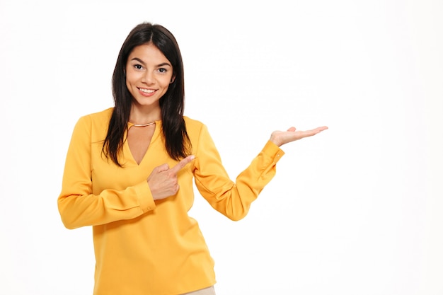 Cheerful young lady in yellow shirt holding copyspace in hand. Free Photo