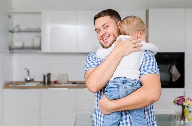 Premium Photo | Cheerful young man hugging a child