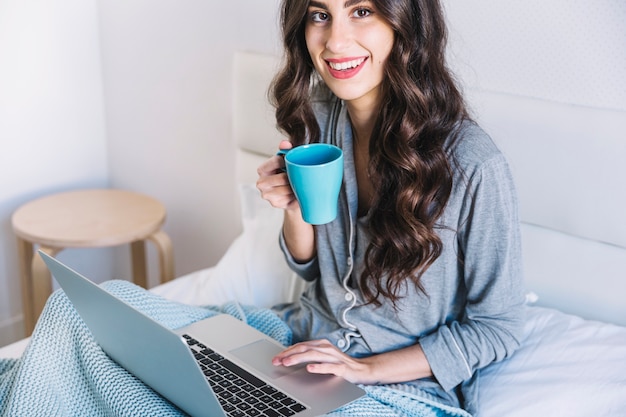 マグカップ ラップトップを持つ明るい若い女性 無料の写真