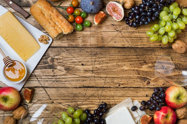 Cheese, wine, baguette grapes figs honey and snacks on the rustic wooden table top with copy space. Premium Photo