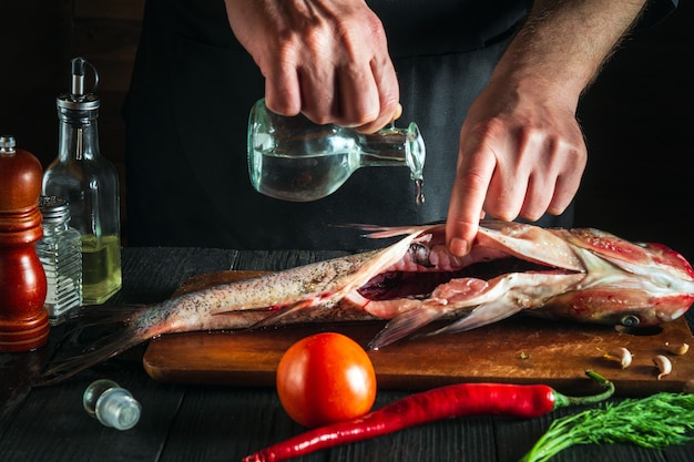 Premium Photo | Chef or cook prepares fresh fish bighead carp with add ...