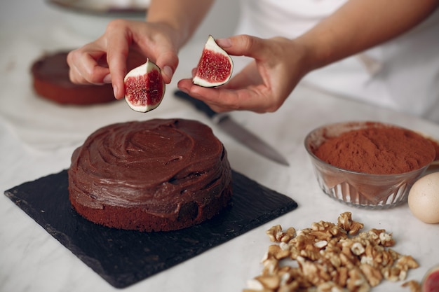 白い服を着たシェフがチョコレートケーキを用意します 女性はデザートを準備しています 女性はケーキを焼きます 無料の写真