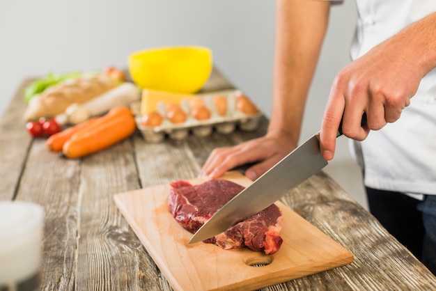 Free Photo | Chef in kitchen cutting meat