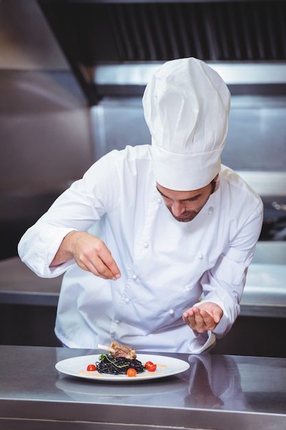 Premium Photo | Chef sprinkling spices on dish