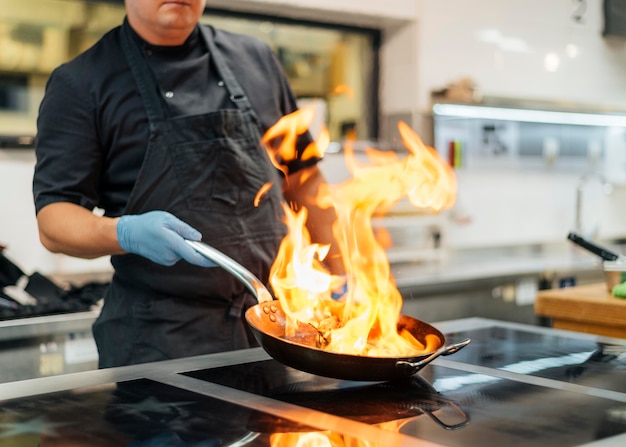 Premium Photo | Chef with apron and gloves flambeing dish