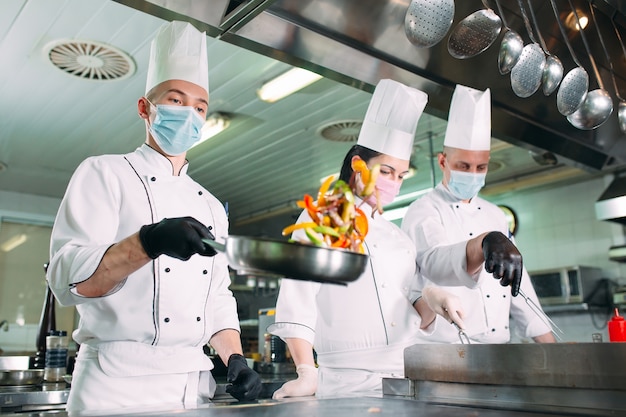 Premium Photo | Chefs in protective masks and gloves prepare food in ...