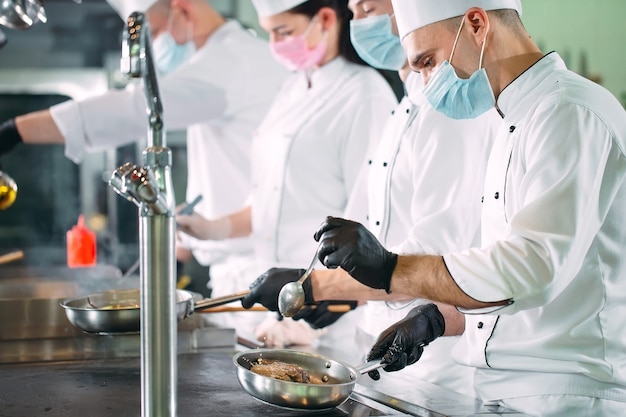 Premium Photo | Chefs in protective masks and gloves prepare food in ...