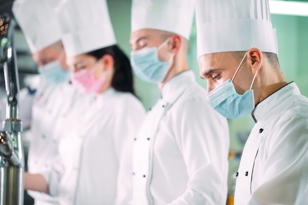 Premium Photo | Chefs in protective masks and gloves prepare food in ...