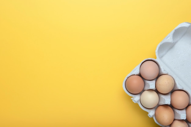 Download Premium Photo Chicken Eggs In A Tray On A Yellow Background View From Above Place For Text PSD Mockup Templates