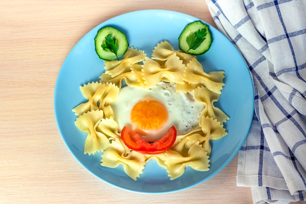 子供の食べ物 面白い食べ物 変な顔の形で目玉焼きと野菜のパスタプレート お子様メニューとランチのコンセプトです プレミアム写真