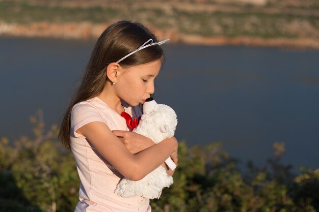 子供の女の子はぬいぐるみクマを抱きしめています プレミアム写真