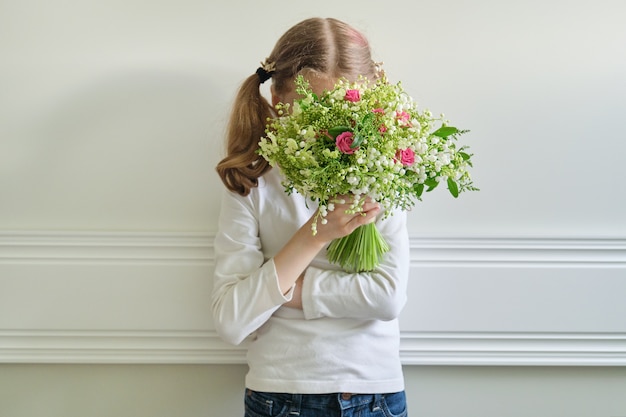 美しい春の花の花束を持つ子供の女の子 プレミアム写真